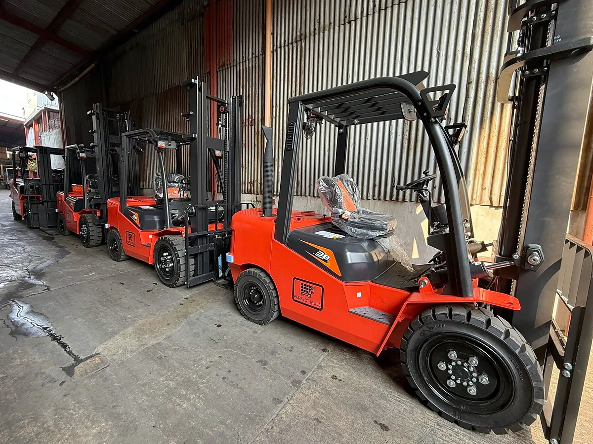 Row of new orange and black Perfect Mule diesel forklifts parked inside a warehouse bay